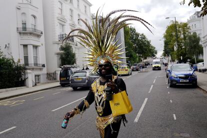 El carnaval de Notting Hill se celebra este año online para evitar la propagación del coronavirus. En la imagen, un hombre vestido con ropa de carnaval  camina por una de las calles que debía recorrer el tradicional desfile.