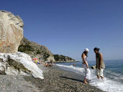 Dos jóvenes se mojan los pies en la playa de Cantarriján, naturista y natural, en Almuñecar.