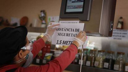 El encargado de un negocio de alimentación en Terrassa (Cataluña) coloca un cartel de advertencia en el mostrador el pasado lunes.