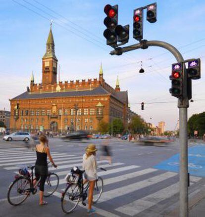 Dos chicas esperan su turno para circular en el centro de Copenhague. Al fondo, el edificio del ayuntamiento de la capital danesa.