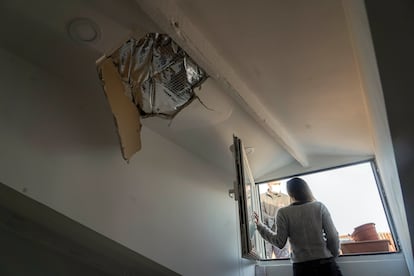 Irene Zoller habla por la ventana de su buhardilla con uno de los obreros que repara el tejado de su edificio.