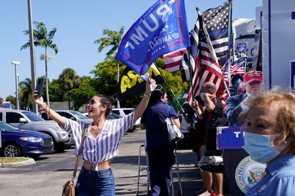 Una joven se toma una foto delante de un centro de votación donde hay seguidores de Trump en Hiealeah, Florida.