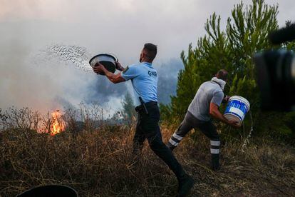 Un oficial de policía y un voluntario trabajan para apagar las llamas en Cascais (Portugal), este martes. 