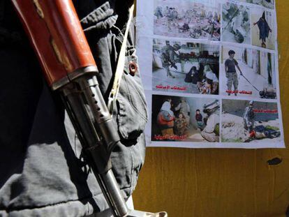 Un hombre armado, junto a un póster de las torturas de Abu Ghraib, este martes en una calle de Saná, la capital de Yemen. En vídeo, el portavoz de la Casa Blanca defiende la operación del Ejército estadounidense.