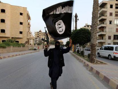 Un miembro de Daesh muestra una bandera del Estado Isl&aacute;mico en Raqqa, en una fotograf&iacute;a de archivo.