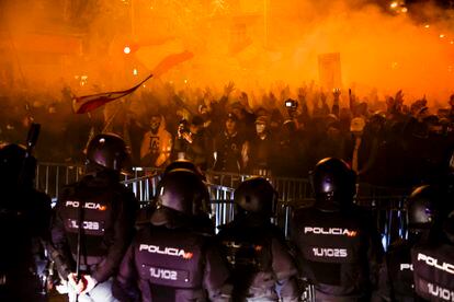 Un grupo de agentes, en fila frente a la valla y a los manifestantes concentrados en los alrededores de la sede del PSOE en la calle de Ferraz de Madrid, este martes.