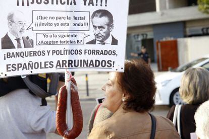 Una mujer sostiene una pancarta contra Rodrigo Rato y Miguel Blesa en la puerta de la Audiencia Nacional durante el juicio contra ambos.