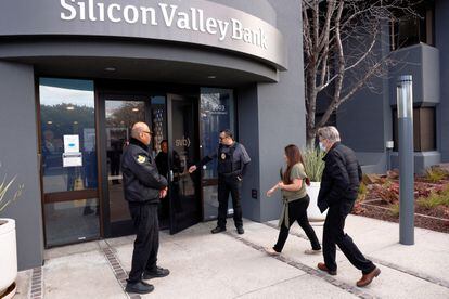 Policías escoltan clientes y trabajadores en una sucursal de Silicon Valley Bank.