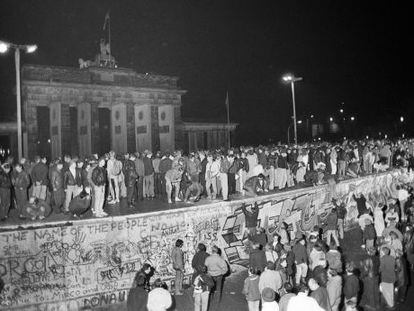Ciudadanos de Berl&iacute;n Este y Berl&iacute;n Oeste celebran subidos al Muro la apertura de la frontera el 9 de noviembre de 1989