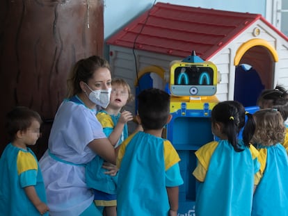 Una educadora muestra a los niños un robot que toma la temperatura en una escuela infantil, esta mañana en Madrid