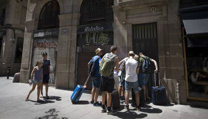 Turistes entren en un pis turístic a Ciutat Vella.
