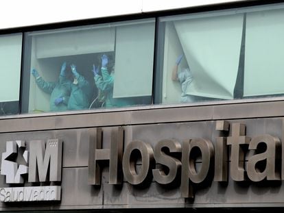 Varios sanitarios saludan desde el Hospital de La Paz, en Madrid.