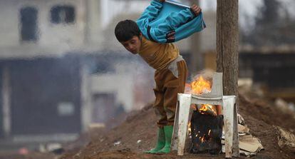 Un ni&ntilde;o se calienta, este jueves, con un fuego en la ciudad rebelde de al-Rai.