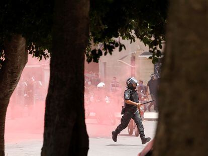 Un policía corre detrás de un grupo de manifestantes en medio de una nube de gas lacrimógeno en la capital de Túnez, el 25 de julio de 2021.