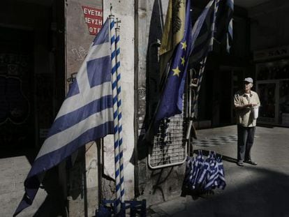 Un ancià davant d'una botiga de banderes gregues i de la UE al centre d'Atenes, aquest dimarts.
