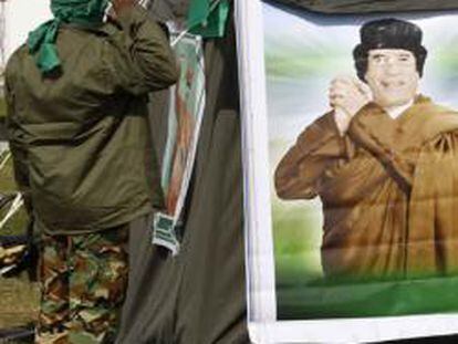 Un miembro del personal de seguridad de Gadafi saluda a una imagen del líder libio