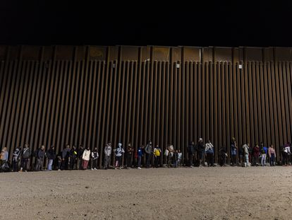Un grupo de inmigrantes esperan en la valla fronteriza con México en Yuma, Arizona (EE UU) antes de ser trasladados a un centro de acogida el 29 de octubre de 2022.