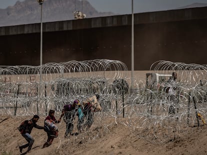 Un grupo de migrantes cruza las alambradas para entregarse a la Patrulla Fronteriza en Ciudad Juárez.