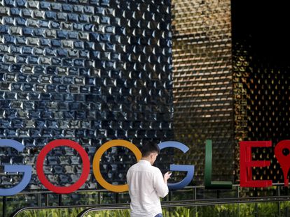 Un hombre mira su móvil mientras camina frente al logo de Google, en Singapur.