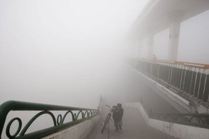 Un hombre empuja su bicicleta en un puente de Harbin (China), 21 de octubre de 2013. El sistema que mide las partículas en suspensión de 2,5 micrones de diámetro o menos, el PM 2,5, superó los 500 microgramos por metro cúbico esta mañana, mientras que la visibilidad se situó por debajo de los 50 metros en el centro de la ciudad, capital de la provincia de Heilongjiang.