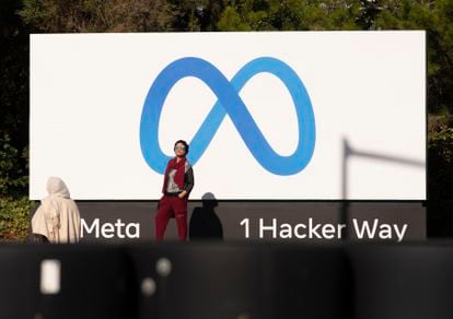 A man takes a photo in front of the Meta logo, at the entrance to Facebook's California offices. 