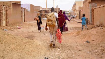 Personas cargan sus pertenencias mientras caminan por una calle de Omdurman, la ciudad gemela de la capital en Sudán, devastada por la guerra, el lunes pasado.