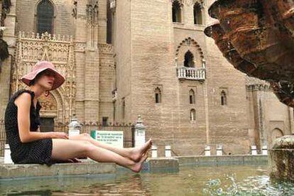 Una solitaria turista trata de refrescarse en la fuente situada al pie de la Giralda durante un paseo por el casco histórico de Sevilla.