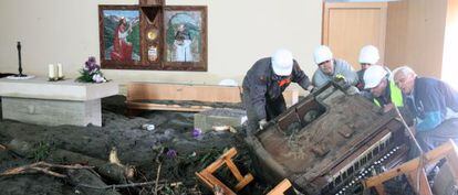 Unos vecinos retiran un piano en la iglesia de Santa Maria, en Mig Aran. 