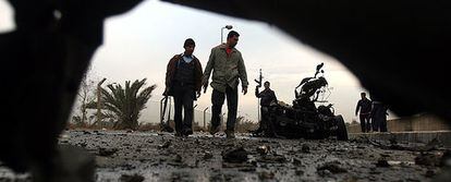 Policías iraquíes, vistos a través de los restos de uno de los coches bomba, inspeccionan el lugar de uno de los atentados en Sadr City.