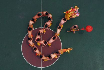 Estudiantes chinos aprenden a realizar una danza de dragón bajo la dirección de un artista local en una zona de juegos en Chongqing, China.