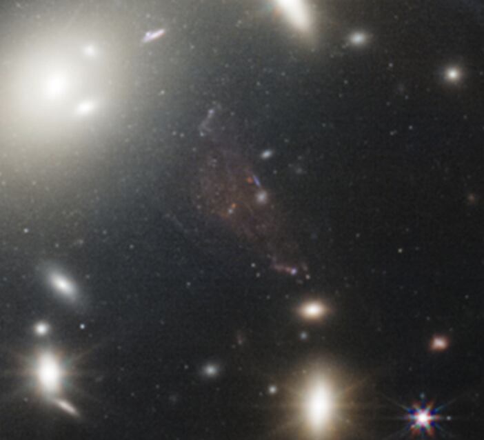 Zona central del cúmulo, donde se ve lo que podría ser una galaxia ultradifusa roja o una estructura de luz intracumular.