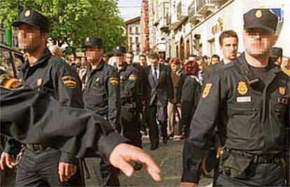 Agentes del Cuerpo Nacional de Policía protegen, ayer, al <i>lehendakari</i>, Juan José Ibarretxe, para evitar agresiones al salir del funeral por Giménez Abad en Jaca.