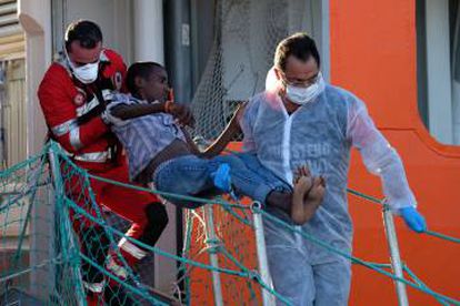 La Cruz Roja italiana ayuda a desembarcar a un migrante en el puerto de Salerno.