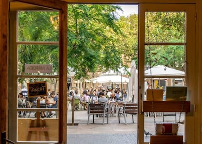 La plaça d’Osca, al barri barceloní de Sants, vista des de l'interior de la llibreria Barra/Llibre.
