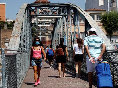 Unos vecinos cruzan el puente de la Torrassa, este sábado, en L'Hospitalet de Llobregat. EFE/Toni Albir