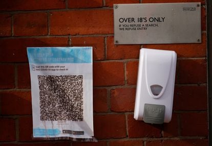 Un código QR para la app del sistema de salud británico en la entrada de un bar en Manchester (Reino Unido) junto a un dispensador de gel.