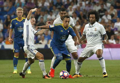 El delantero chileno del Celta de Vigo, Fabián Orellana (c), se lleva el balón ante los jugadores del Real Madrid.