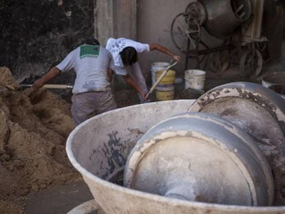 Obreros de la construcci&oacute;n preparan la mezcla con arena y cemento.