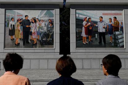Ciudadanos de Corea del Norte rinden homenaje frente a las pinturas de los líderes norcoreanos Kim Il Sung y Kim Jong Il, en una fábrica de seda en Pyongyang.