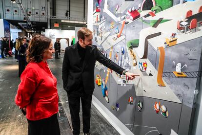 Pepa Bueno, directora de EL PAÍS, y el artista Edgar Plans ante la obra 'My Daily News' que ha creado para el estand del periódico en Arco.