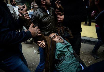 Dos manifestantes opositores evacuan a un herido en El Cairo este s&aacute;bado.