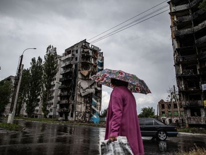 Una mujer camina ante unos edificios de apartamentos destruidos por los bombardeos en la ciudad ucrania de Borodianka.