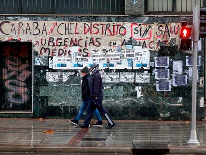 Dos personas pasan ante una pintada que reivindica la Sanidad Pública en Madrid.