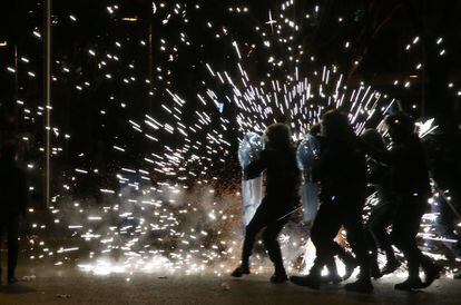 Varios policías antidisturbios se protegen con sus escudos al explotar un cohete lanzado en la plaza de Colón de Madrid por los manifestantes en los incidentes posteriores a la "Marcha por la dignidad".