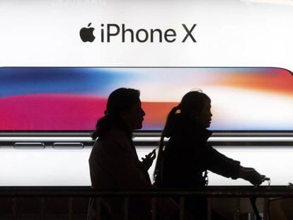 Dos personas pasan por delante de un anuncio del iPhone X. 