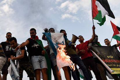 Activistas queman una bandera israelí mientras gritan consignas frente a la embajada de Israel en Atenas, Grecia.