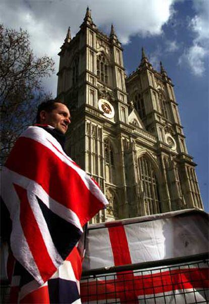 Un ciudadano británico se envuelve en la bandera Union Jack ante la abadía de Westminster.
