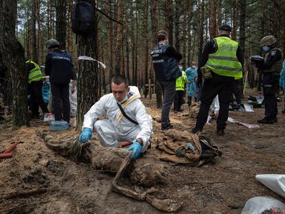 EDS NOTE: GRAPHIC CONTENT - An expert examines a body during an exhumation in the recently retaken area of Izium, Ukraine, Friday, Sept. 16, 2022. Ukrainian authorities discovered a mass burial site near the recaptured city of Izium that contained hundreds of graves. It was not clear who was buried in many of the plots or how all of them died, though witnesses and a Ukrainian investigator said some were shot and others were killed by artillery fire, mines or airstrikes. (AP Photo/Evgeniy Maloletka)