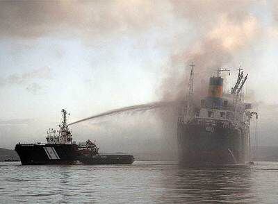 Una embarcación de Salvamento trata de sofocar las llamas del mercante <i>Doxa</i>, en la ría de Arousa.