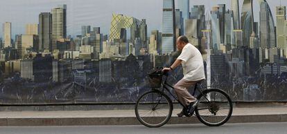 Un ciclista pasa junto a un cartel del dise&ntilde;o de un proyecto de construcci&oacute;n en Pek&iacute;n.